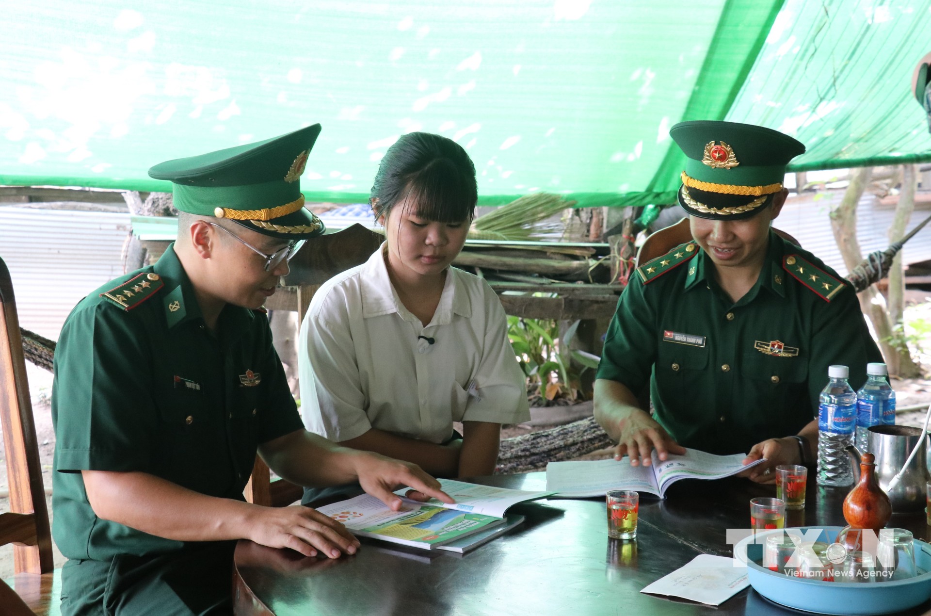 Đại úy Phạm Việt Tiến (đeo kính) thăm hỏi, động viên học sinh được Đồn Biên phòng Cửa khẩu Mỹ Quý Tây nhận nuôi, tiếp thêm động lực để em vượt qua khó khăn, vươn lên trong học tập. (Ảnh: Bùi Giang/TTXVN)